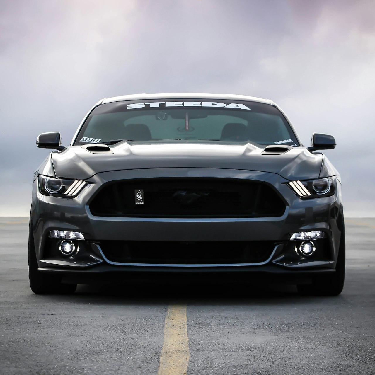 A dark grey Ford Mustang parked on an empty asphalt parking lot